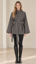 Front view of woman wearing grey plaid belted cape jacket with stand collar and wide sleeves