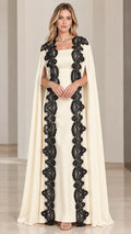 Front view of cream cape maxi dress with contrast black lace trim