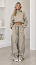 Front full-length view of model wearing taupe cropped windbreaker and wide-leg track pants set
