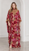 Front full-length view of model wearing burgundy floral velvet kaftan dress with embellished neckline