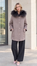 Front full-length view of model wearing taupe faux fur hooded parka coat with black wide-leg trousers
