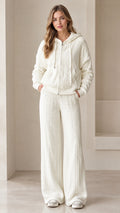 Front full-length view of woman wearing white cable knit zip-up hoodie and matching wide leg pants