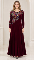 Front view of woman wearing burgundy velvet maxi dress with colorful embroidered leaf details