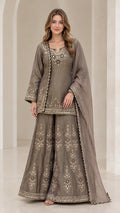 Front view of woman wearing taupe grey embroidered kurti sharara suit set with dupatta