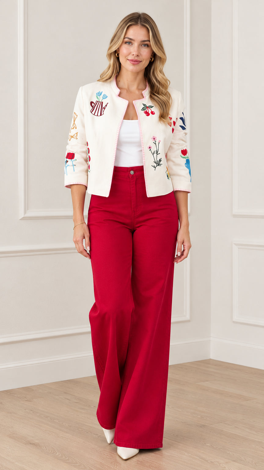 Front view of model wearing cream embroidered cropped jacket with red wide-leg trousers