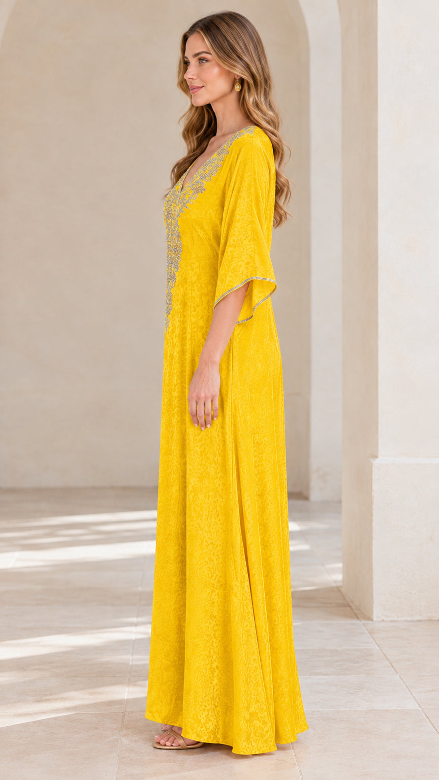Side profile view of woman wearing yellow floor-length kaftan dress with kimono sleeves