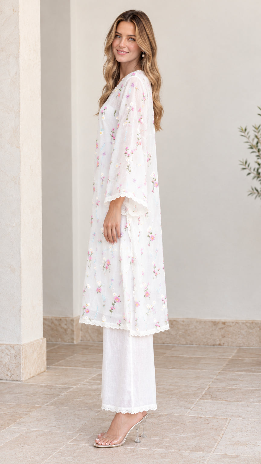 Side profile view of woman wearing white floral embroidered tunic and matching trousers