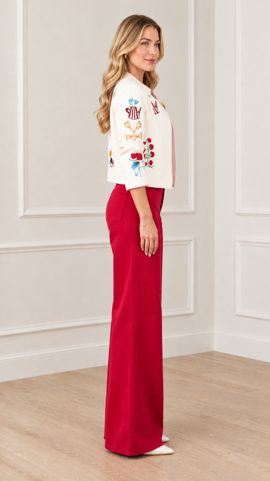 Side profile view of cream whimsical embroidered cropped jacket