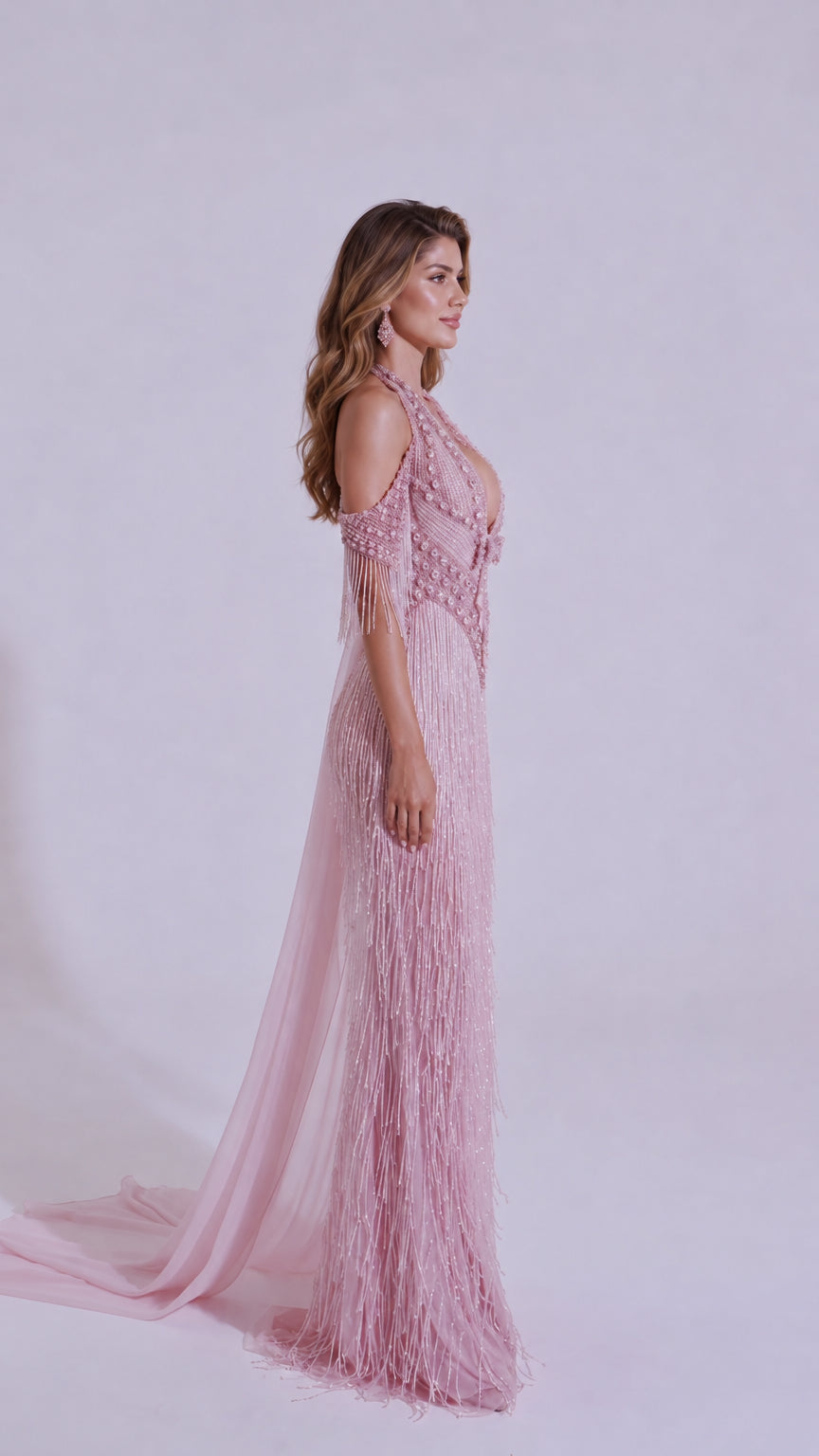 Side profile of Blush Pink embellished fringe evening gown showing flowing cape
