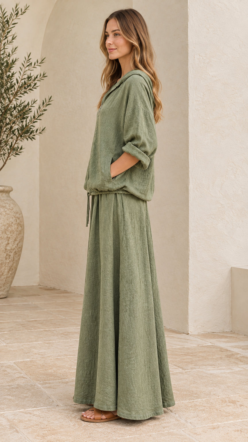 Side angle view of woman in sage green two-piece maxi skirt and hoodie set
