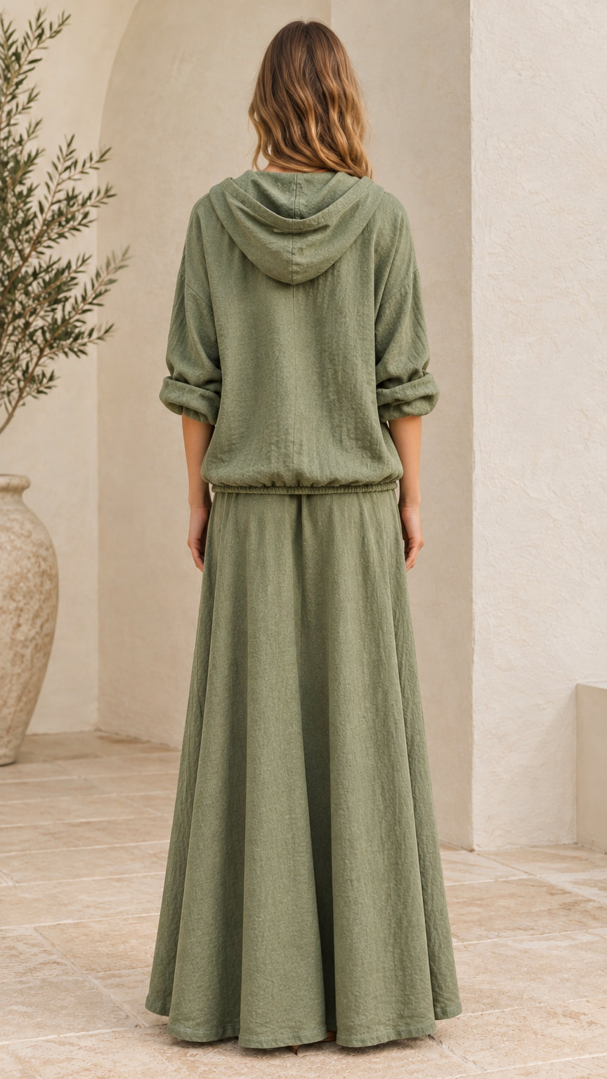 Back view of woman wearing sage green hooded top and long maxi skirt