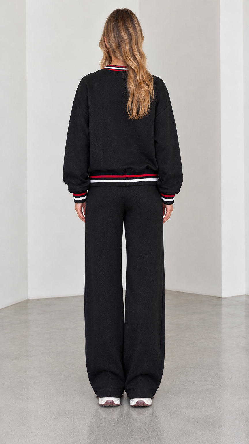 Back view of model wearing black zip-up lounge jacket and matching wide pants