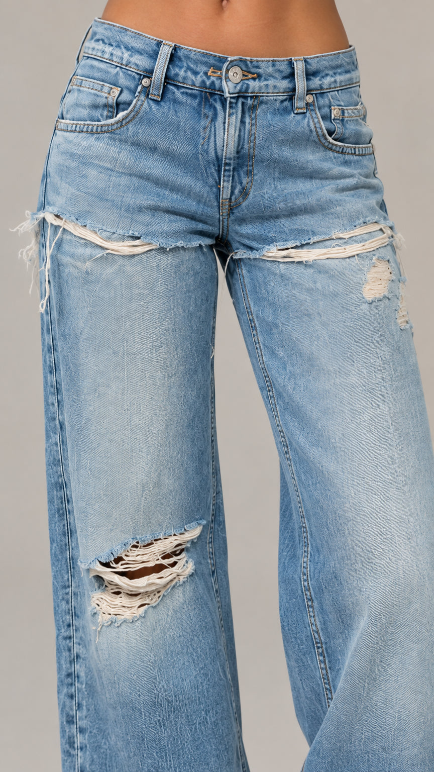 Close-up detail of front thigh distressing on medium blue denim jeans