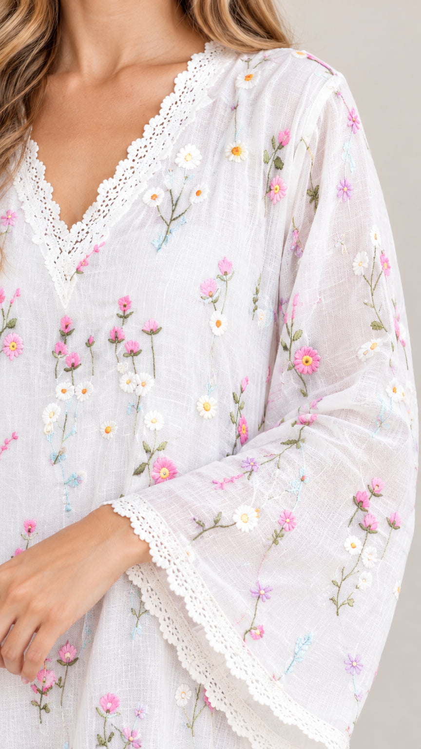 Close-up detail of V-neckline, floral embroidery, and crochet lace trim on white tunic
