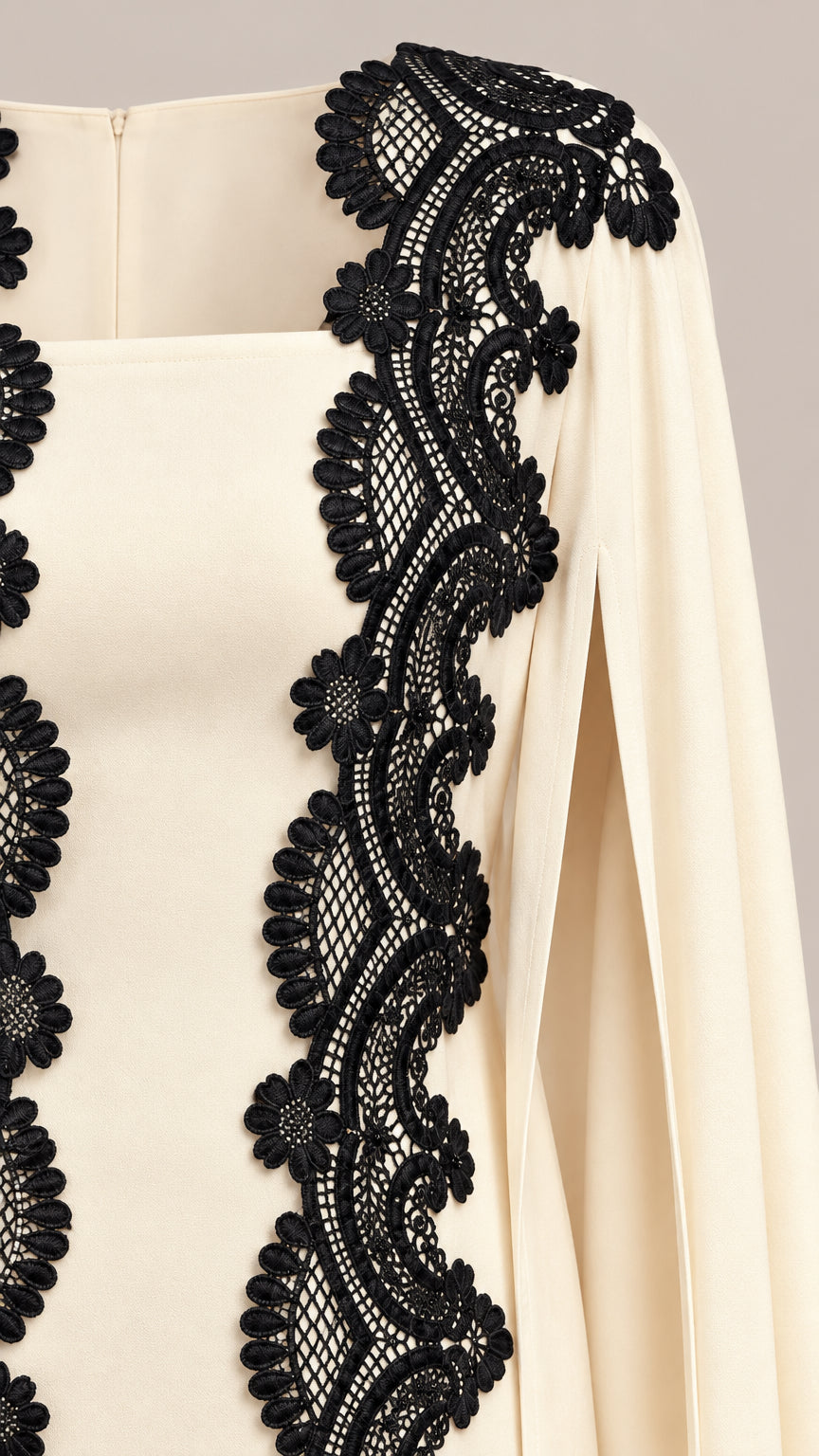 Close-up detail of intricate black floral lace trim on cream neckline