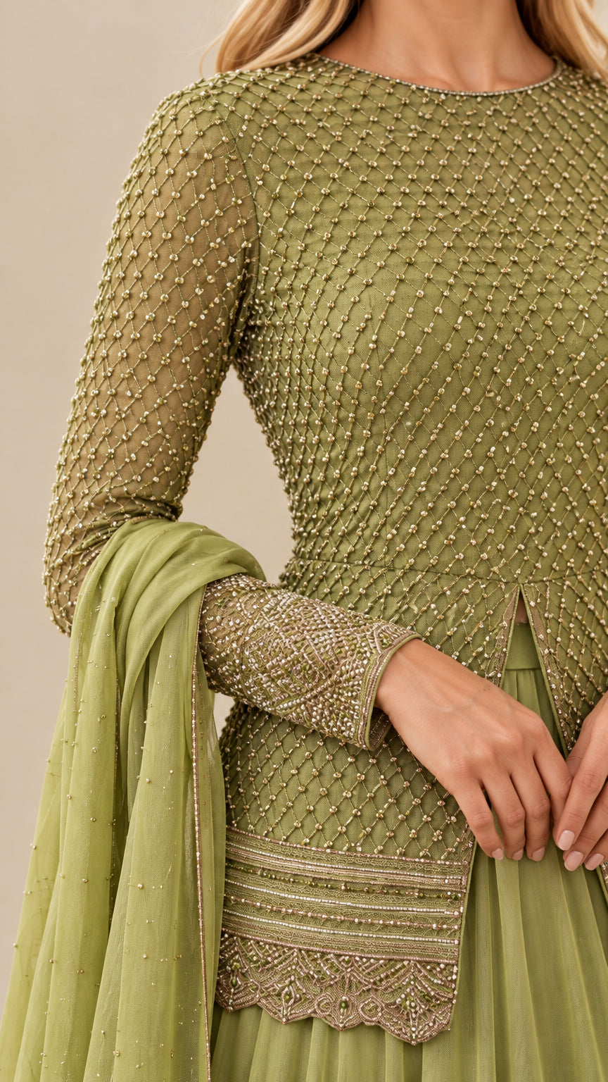 Close-up detail of geometric beadwork, scalloped embroidered hem, and cuff accents on sage green top