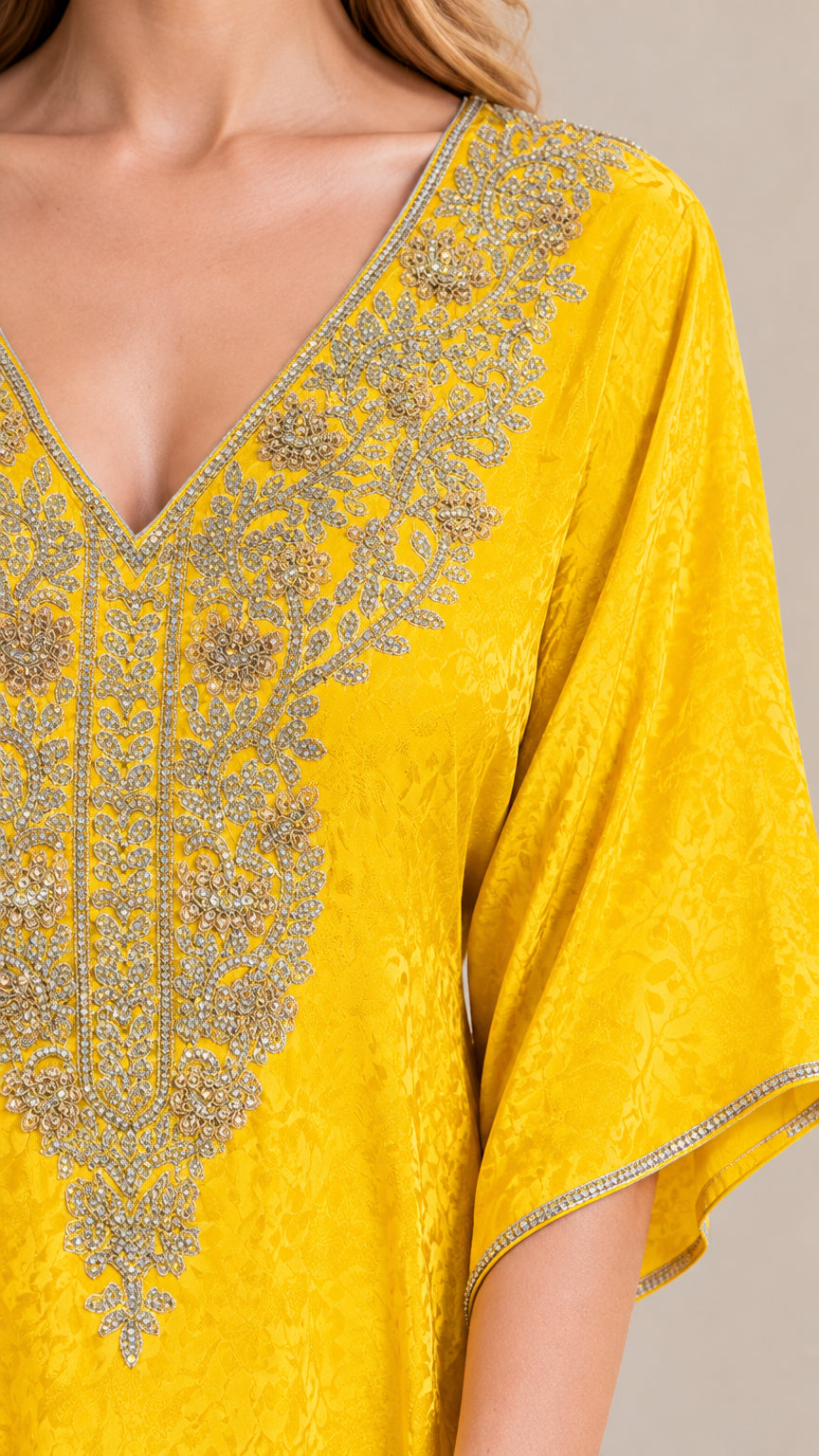 Close-up detail of ornate metallic gold embroidery on the V-neckline of the yellow kaftan